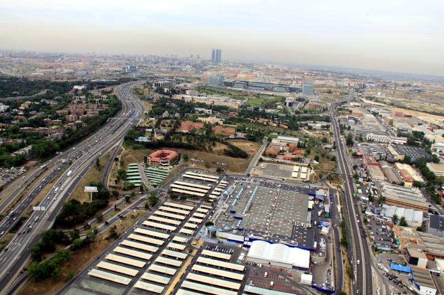 Vista aérea de la zona comercial y empresarial de Alcobendas con la cercana ciudad de Madrid y sus icónicas torres al fondo.