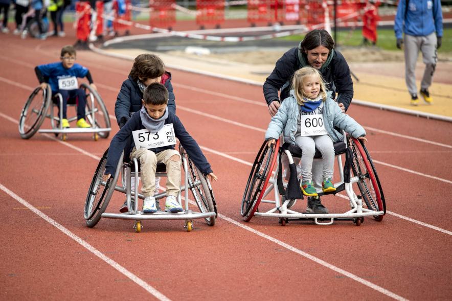 Niños participando en la carrera con silla adaptada